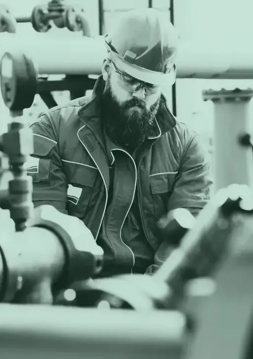 Oilfield worker in safety gear inspecting equipment, representing the hardworking professionals Bison Payments supports with financial solutions.